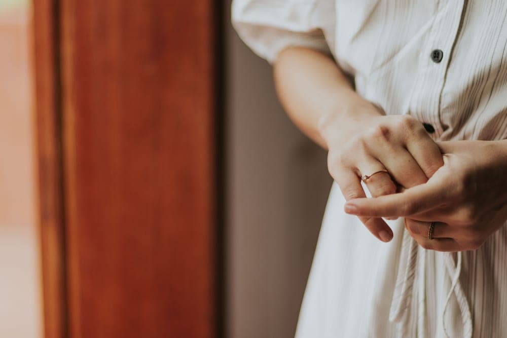 A woman in a white dress adjusting a thin gold ring