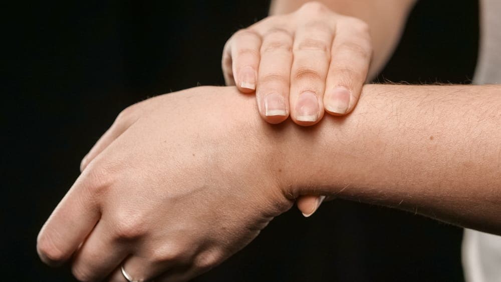 Fingers pressing the inside of a wrist to check a pulse